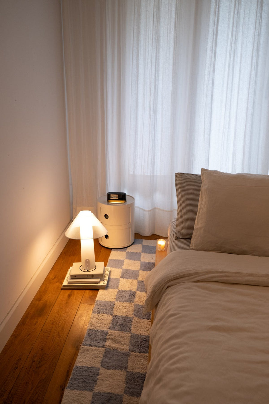 Bedroom at dusk with the Loftie Lamp and Clock glowing by the bed