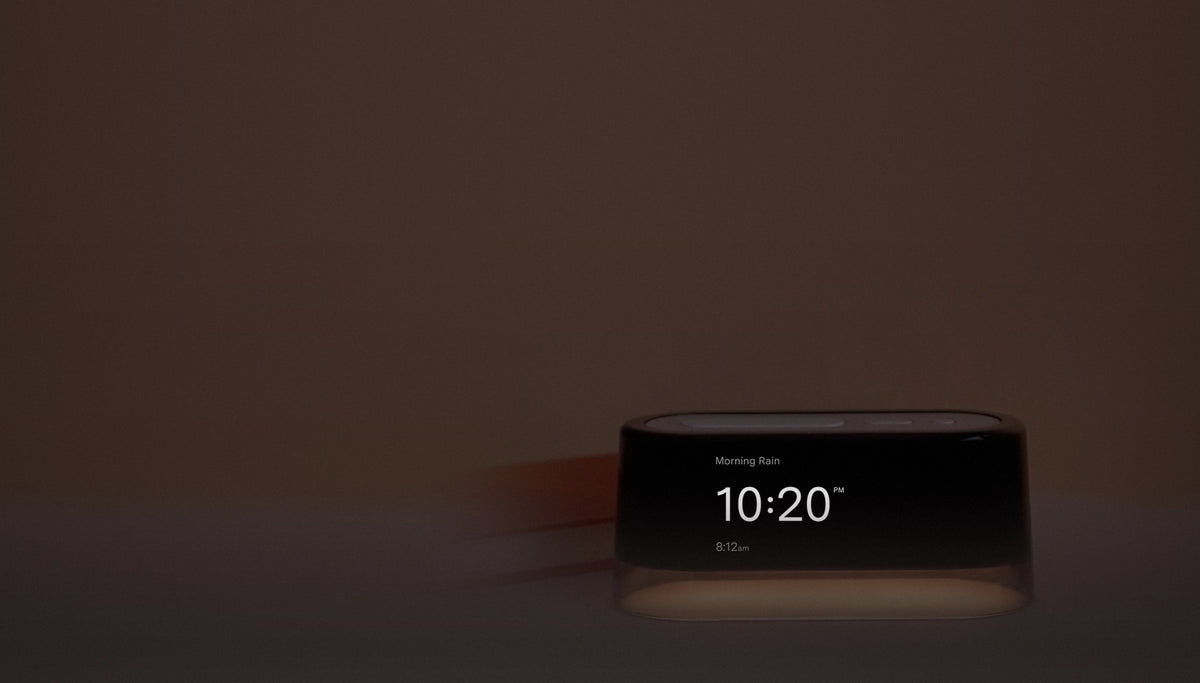 Loftie Clock glowing on a nightstand in a dark bedroom